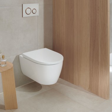 Bílé keramické WC v koupelně s dřevěnými prvky vypadá i po mnoha letech stále moderně (zde: WC Geberit iCon a ovládací deska Geberit Sigma20).