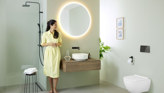 Žena v koupelně vybavené zrcadlem Geberit Option a umyvadlem Geberit VariForm