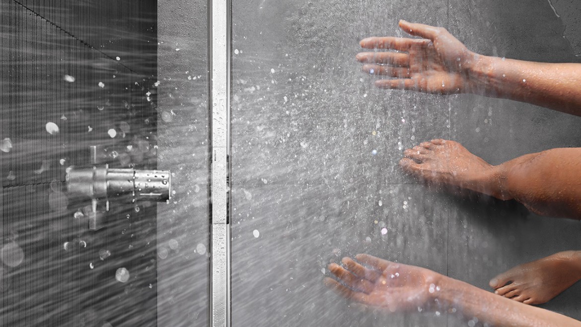 Osoba sprchující se ve sprše v úrovni podlahy se sprchovým kanálkem Geberit CleanLine