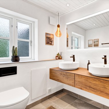 Světlá zrekonstruovaná koupelna se dvěma kulatými umyvadly, velkým zrcadlem a dřevěným koupelnovým nábytkem (© @triner2 a @strandparken3)