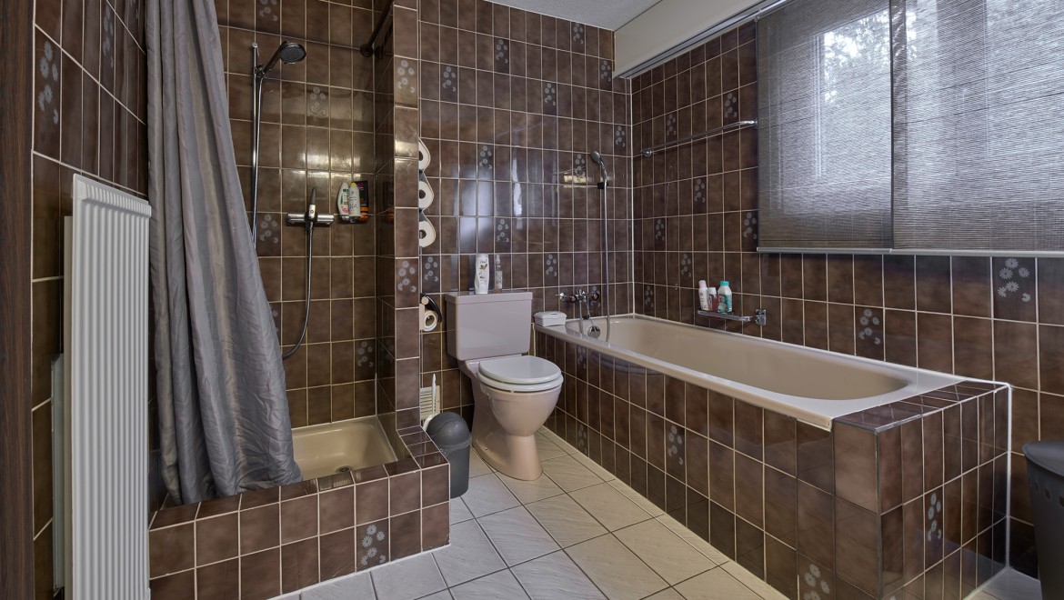 Koupelna s úzkým sprchovým koutem, vanou a stojícím WC