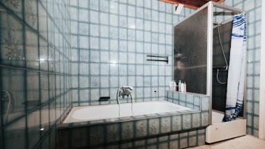 Koupelna s modrými obklady, sprchovým koutem a vanou