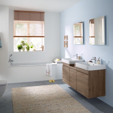 Rodinná koupelna se světle modrou stěnou a koupelnovým nábytkem v barvě hickory, zrcadlovou skříňkou, ovládací deskou a keramickými spotřebiči Geberit