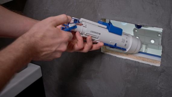 Muž instaluje splachovací ventil Geberit do skryté splachovací nádržky (© Ben Huggler) Muž instaluje splachovací ventil Geberit do skryté splachovací nádržky (© Ben Huggler)