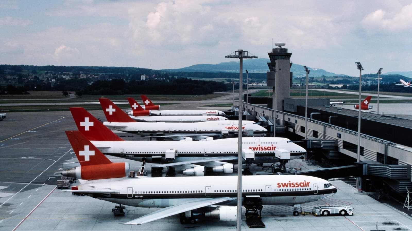 Letadla bývalé společnosti Swissair parkují v přístavišti terminálu A v Curychu v 80. letech 20. století (© ETH-Bibliothek Zürich) Letadla bývalé společnosti Swissair parkují v přístavišti terminálu A v Curychu v 80. letech 20. století (© ETH-Bibliothek Zürich)